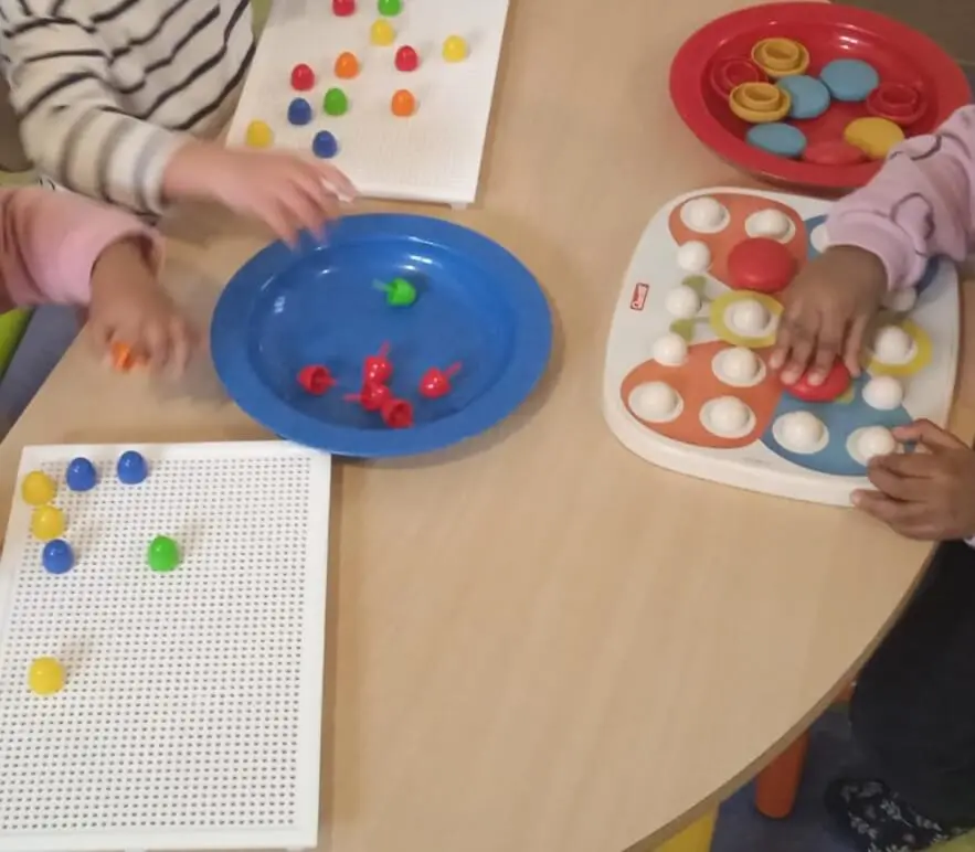 Mains d’enfants manipulant de petites pièces colorées