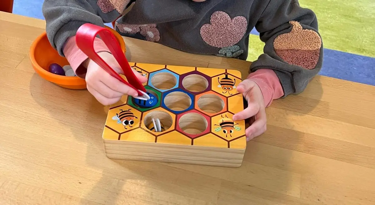 Enfant jouant avec un jeu en bois sur le thème des abeilles