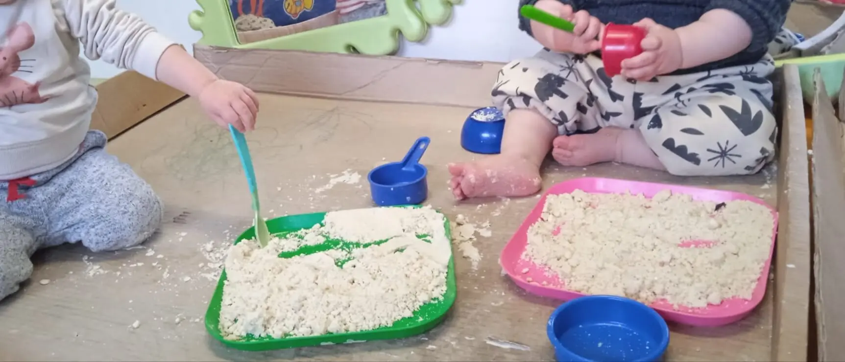 Enfants explorant des bacs sensoriels avec des pinceaux